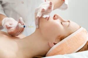 Cosmetologist performing a Kybella® injection to reduce submental fat, contouring the chin and enhancing facial definition for a sculpted appearance.