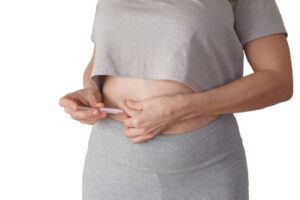 Close-up of hands administering GLP-1 weight loss injection into abdomen. Close-up of hands administering GLP-1 weight loss injection into abdomen.