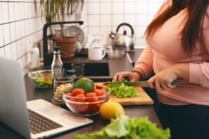 Overweight woman cooking a nutritious meal while practicing intuitive eating on GLP-1s
