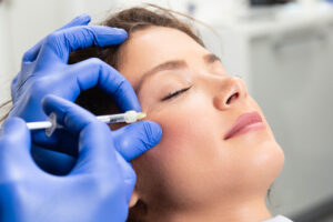 Beautiful young woman receiving Sculptra biostimulator injections around her eyes to improve facial volume.